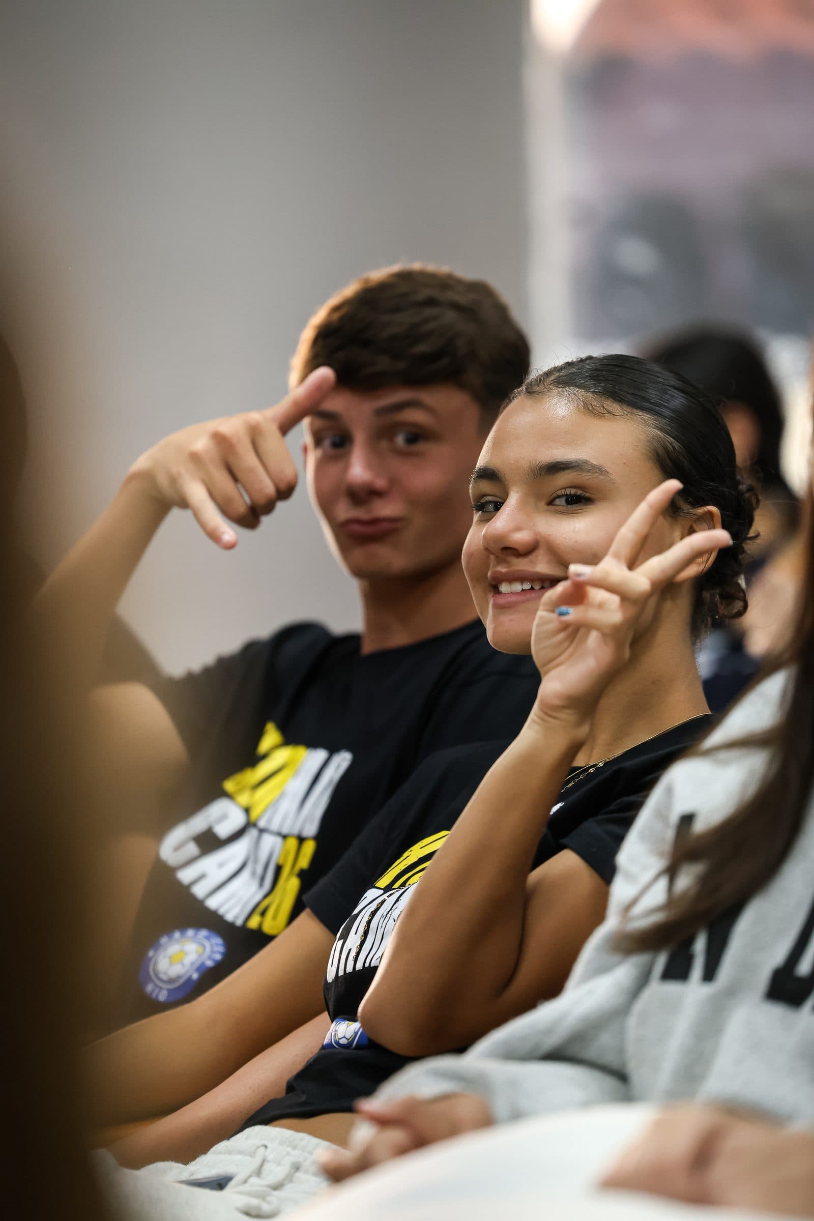 Acampantes sentados lado a lado em momento de descanso, sorrindo para a camera